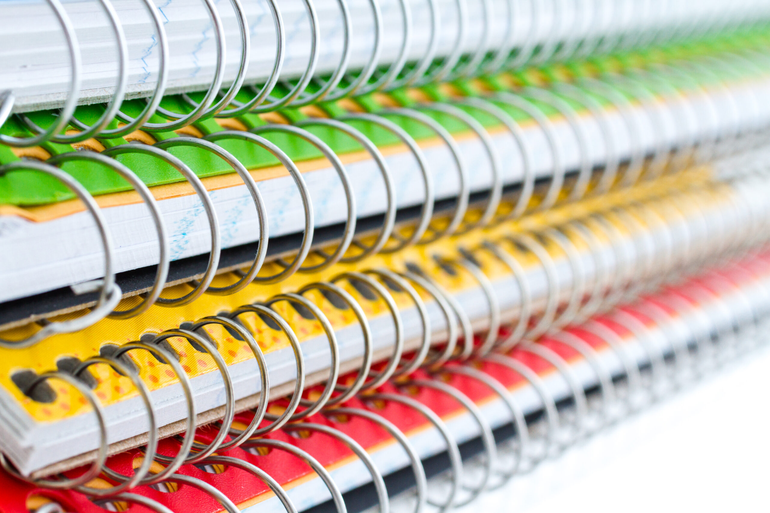 Multicolored spiral notebooks on a white background.