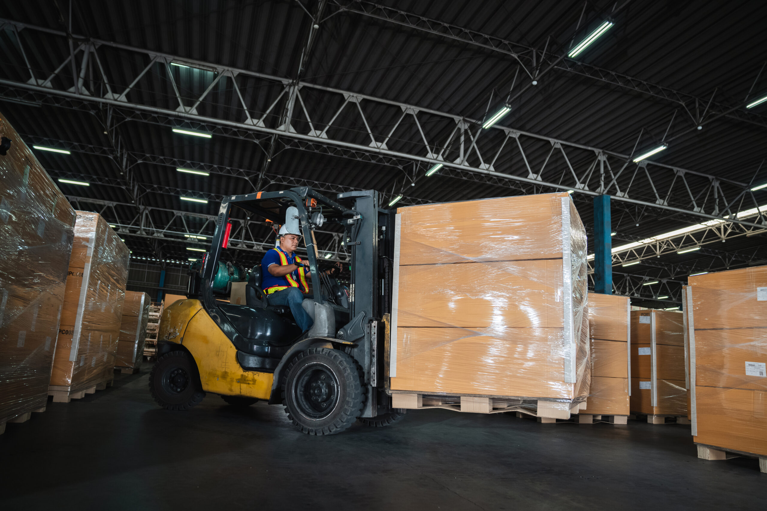 Warehouse worker workers with forklift in a warehouse. Use forklift operator moves packages. Concept industrial and commercial.